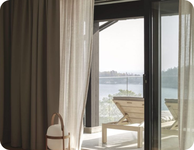 White curtains frame a patio view with a wooden table and chairs.
