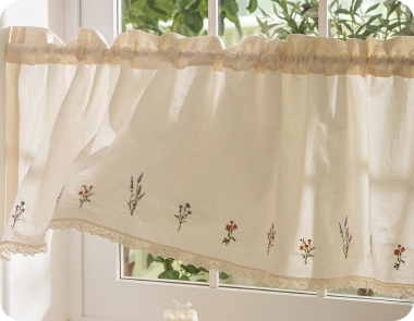A cream valance curtain with floral embroidery hangs in a kitchen window.